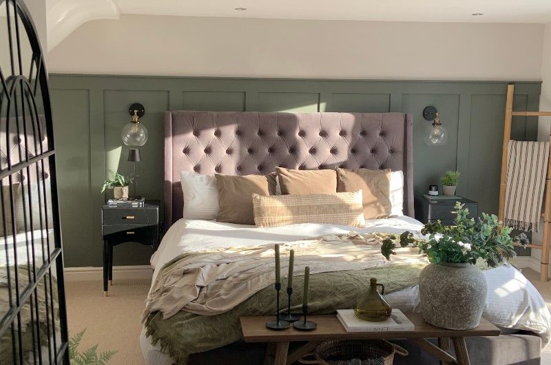 A calm green bedroom design with panelling and a central bed.