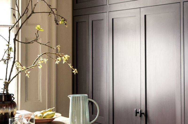 A minimalist scheme with classic cabinetry and olive tiles on the island, with plates and glasses ready for entertaining.