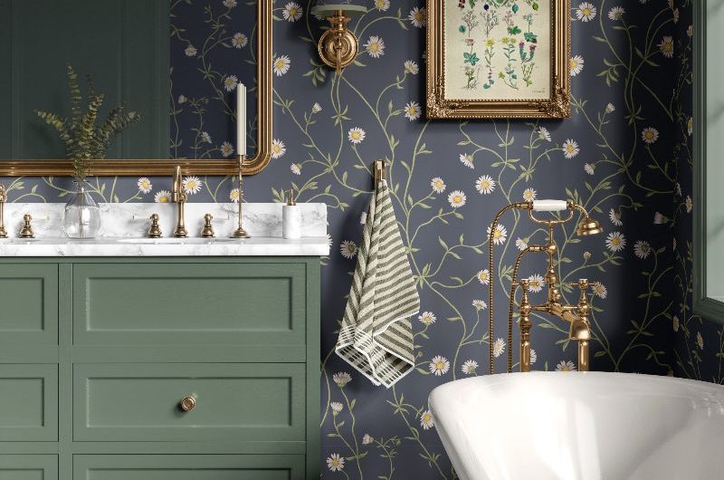 Charming bathroom design with green furniture, marble surfaces, aged brassware, daisy patterned wallpaper and a freestanding tub.