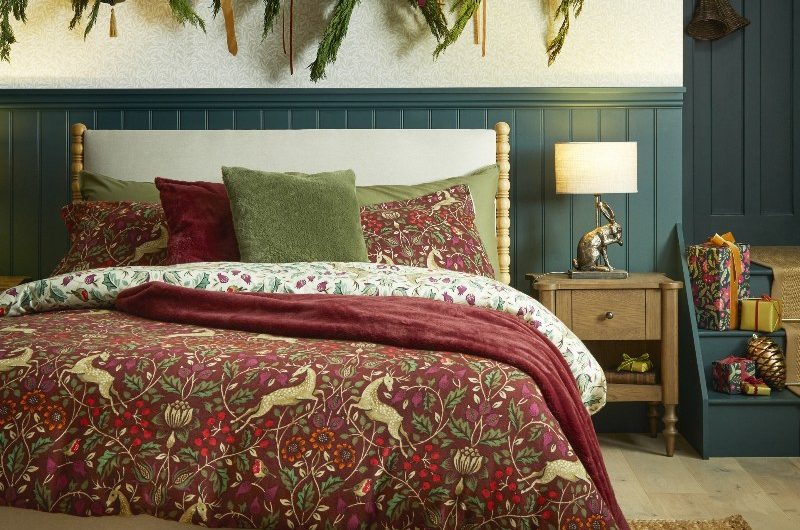 A bedroom design with nature-inspired bed linen, jute rug, blue wall panelling and Christmas garlands.