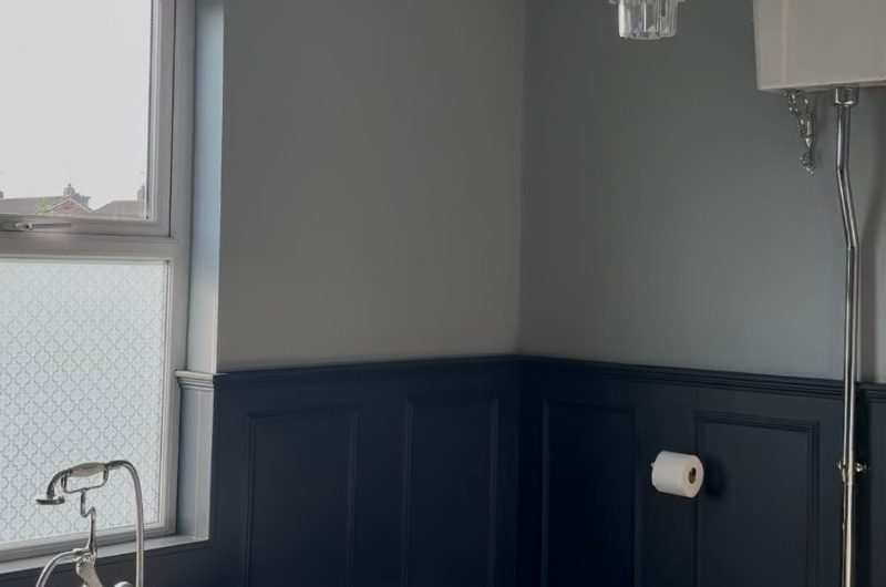 A classic bathroom renovation with navy panelling and white sanitaryware.