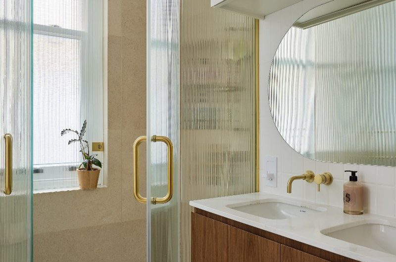 A shower zone with white tray, fluted enclosure and a double vanity unit made from wood.